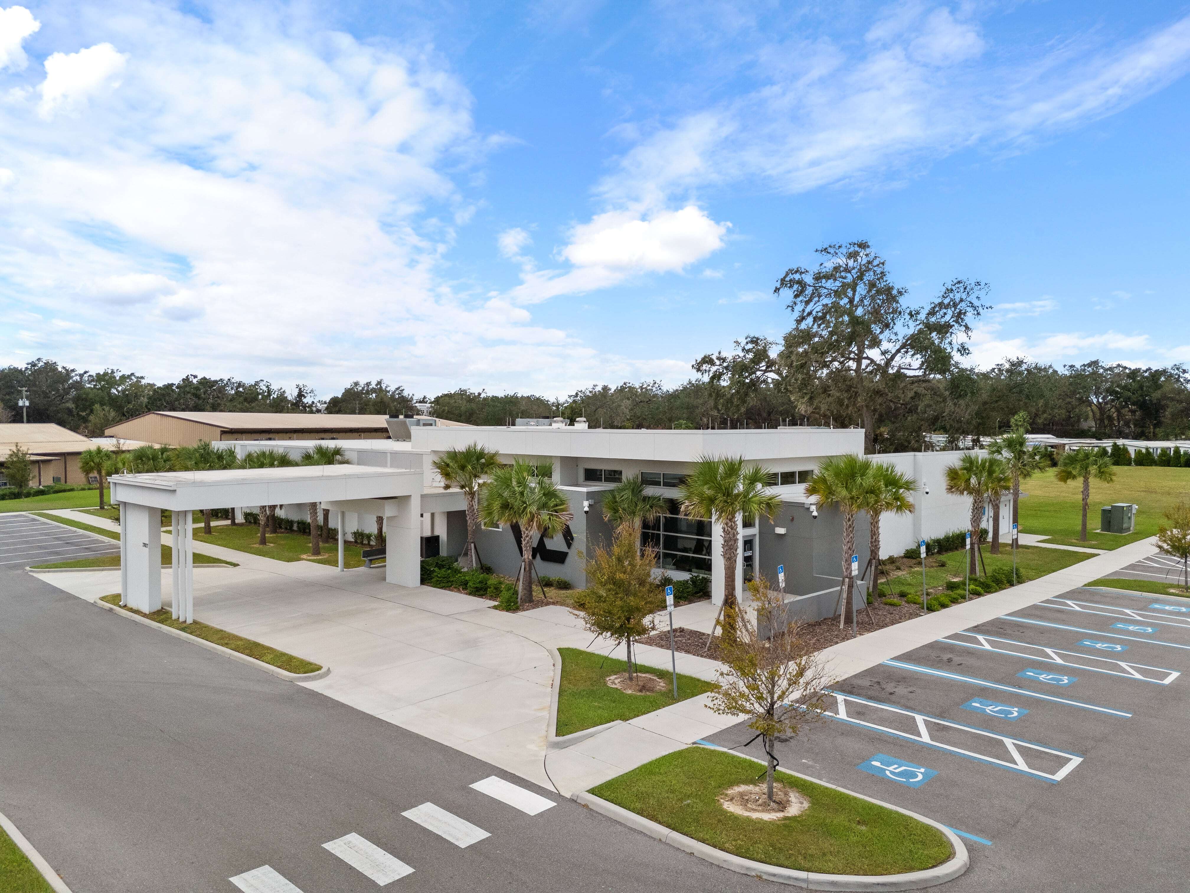 Wide parking lot in front of Zephyrhills VA clinic with view of building entrance and palm trees
