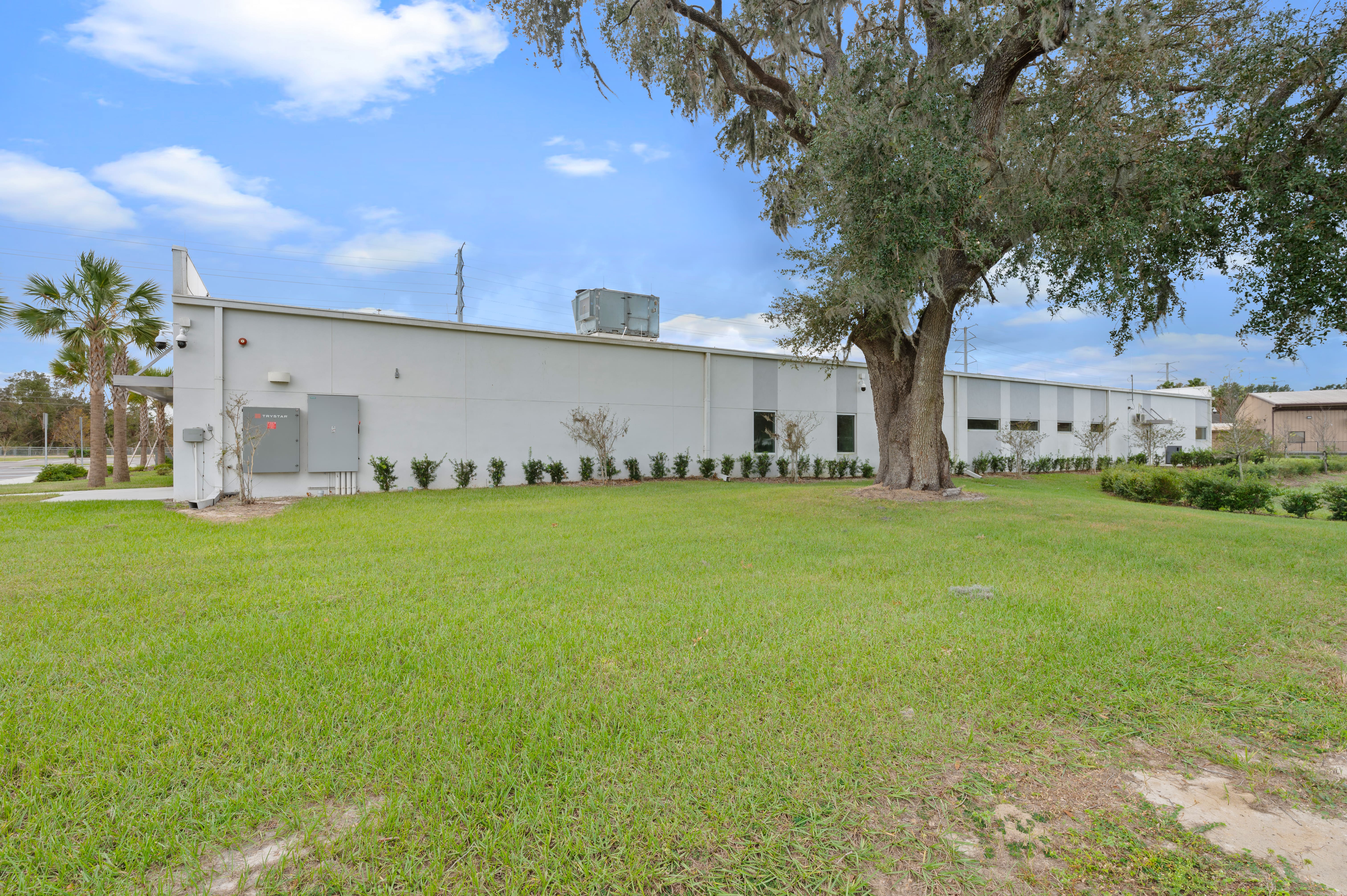 Rear view of the clinic building featuring a flat roofline, maintenance access points, and surrounding greenery.